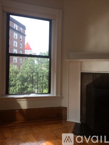 A window with a view of a red building and trees.
