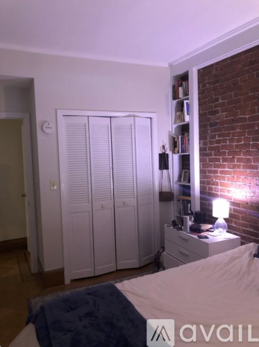 A bedroom with a bed, a wardrobe, and a nightstand with a lamp.
