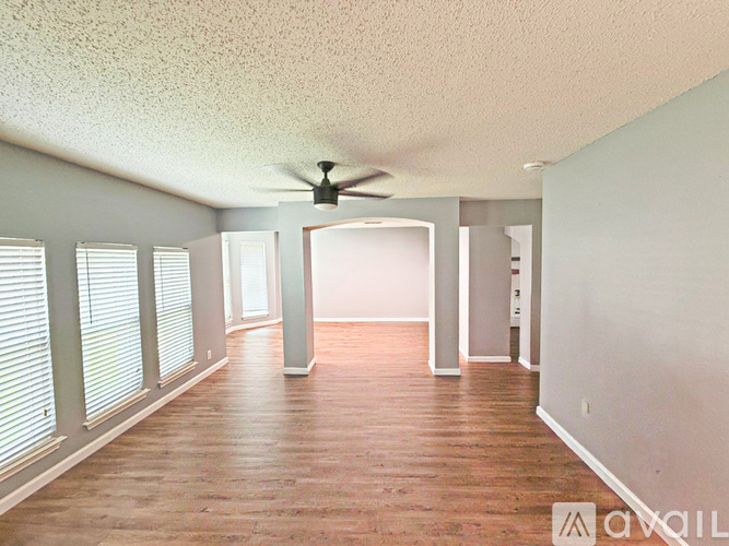 A room with a ceiling fan and wooden flooring.