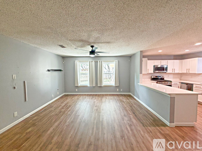 A spacious room with wooden flooring and a ceiling fan.