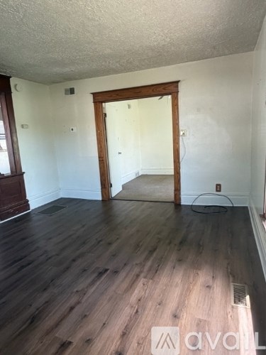 A room with wooden floors and a doorway leading to another room.
