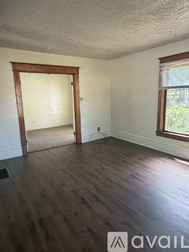 A room with wooden floors and a window with blinds.