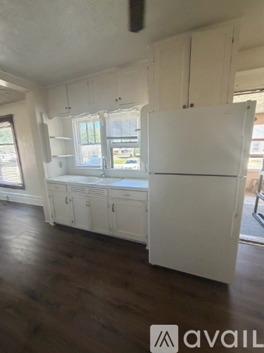 A kitchen with white cabinets and a white fridge.