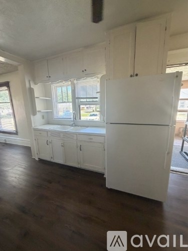 A kitchen with white cabinets and a white fridge.