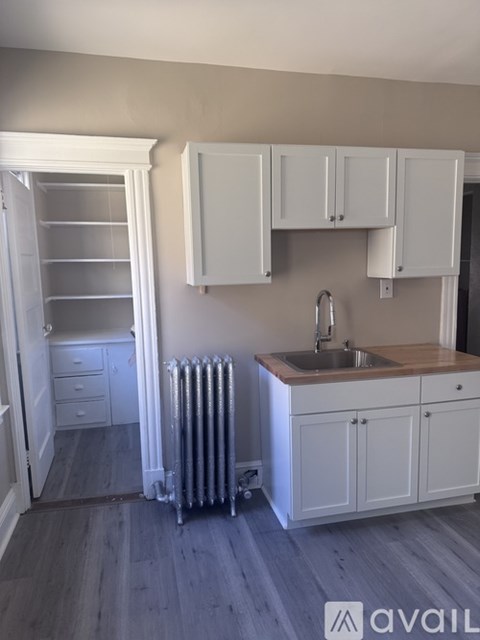 A kitchen with white cabinets and a wooden countertop.