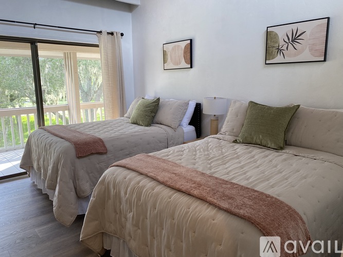 Two beds with pillows and blankets in a room with a window.