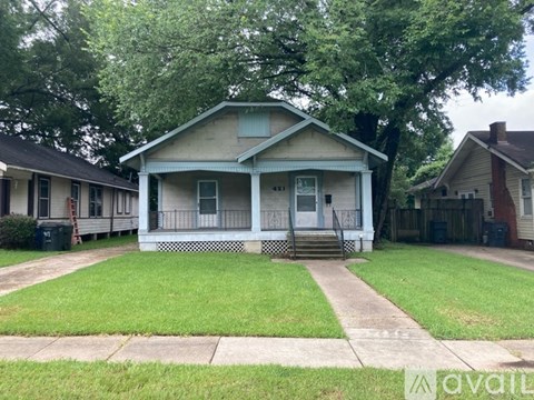 A blue house with a white porch and a green trash can.