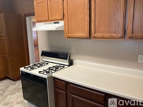A kitchen with a stove and wooden cabinets.