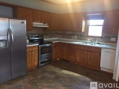 A kitchen with wooden cabinets and a stainless steel refrigerator.