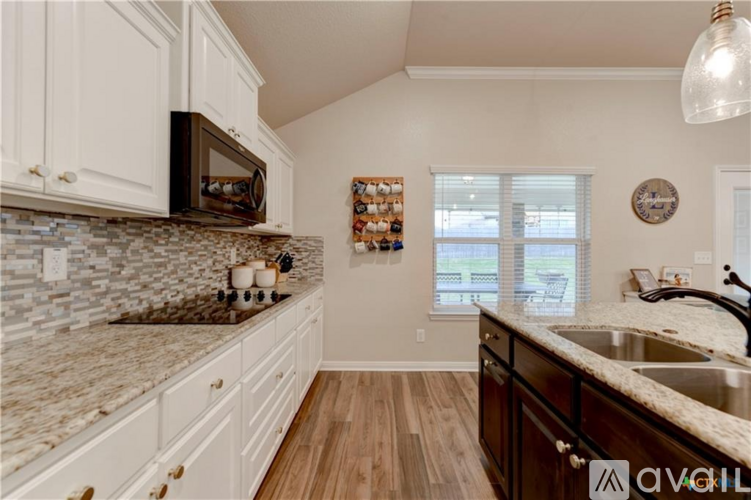A kitchen with white cabinets and a granite countertop.