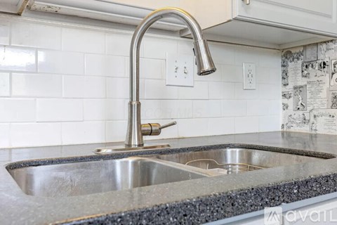 A kitchen sink with a chrome faucet and a white tile backsplash.