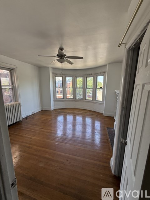 A room with a ceiling fan and wooden floors.