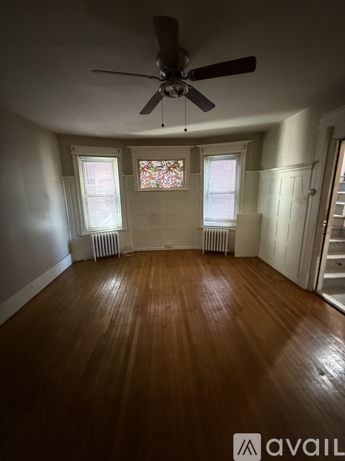 A room with a ceiling fan and wooden flooring.