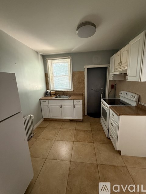 A kitchen with white cabinets and a tiled floor.