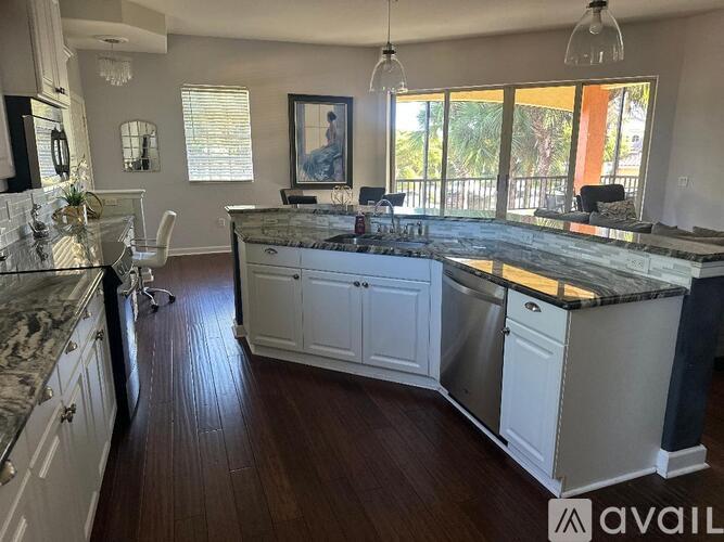 A kitchen with white cabinets and a marble countertop.