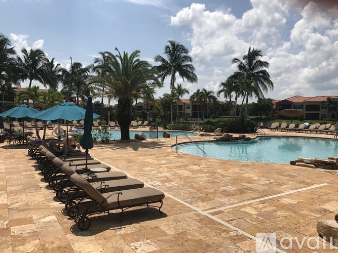 A pool area with sun loungers and palm trees.