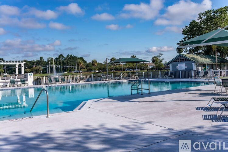 A large outdoor swimming pool with sun loungers and a green umbrella.