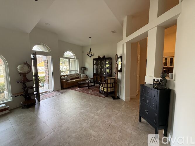 A spacious living room with a sofa, chairs, and a chandelier.