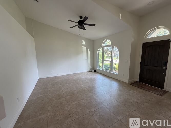 A spacious room with a ceiling fan and large windows.
