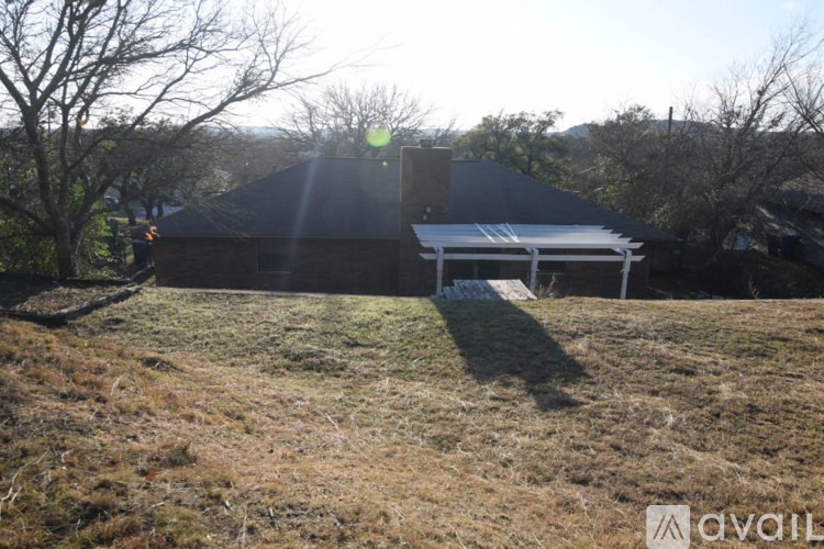 A house with a covered patio is surrounded by trees.