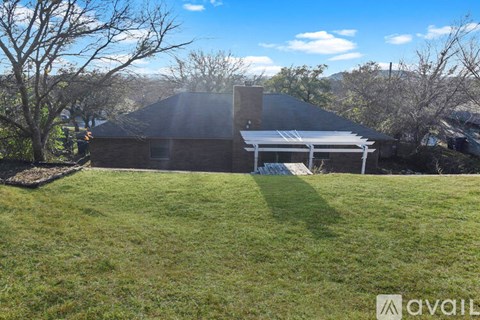 A house with a covered patio is surrounded by trees.