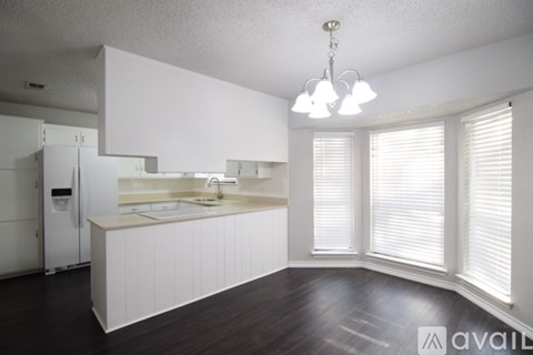A kitchen with white cabinets and a white refrigerator.