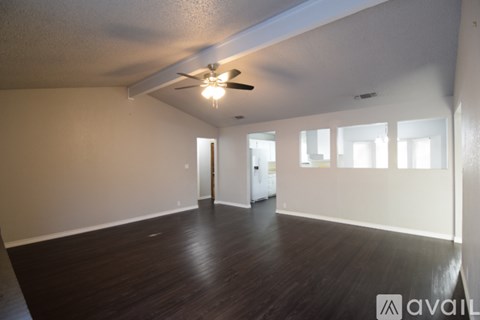 A spacious room with wooden floors and a ceiling fan.