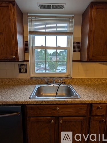 A kitchen with wooden cabinets and a window overlooking a parking lot.