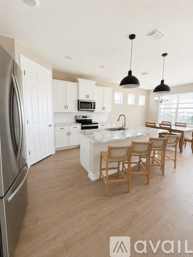 A kitchen with a refrigerator, sink, and dining table.