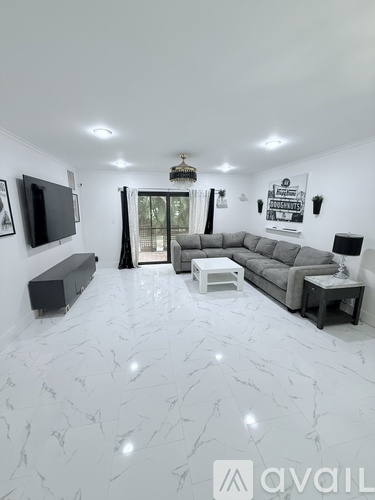 A living room with a grey sofa and a television on the wall.