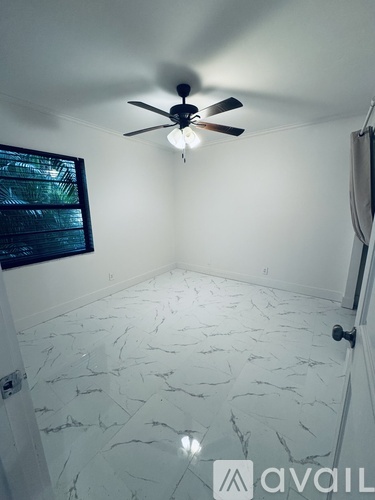 A room with a ceiling fan and a marble floor.