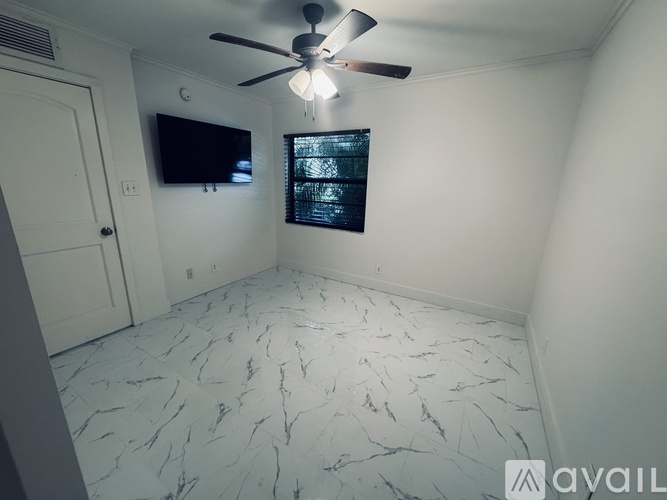 A room with a ceiling fan and a flat screen TV mounted on the wall.