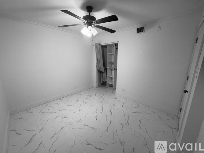 A room with a ceiling fan and marble flooring.