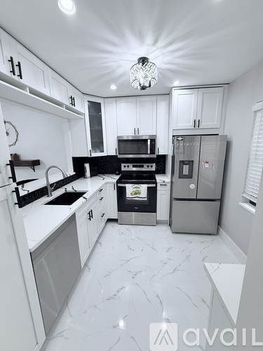 A modern kitchen with white cabinets and a marble floor.