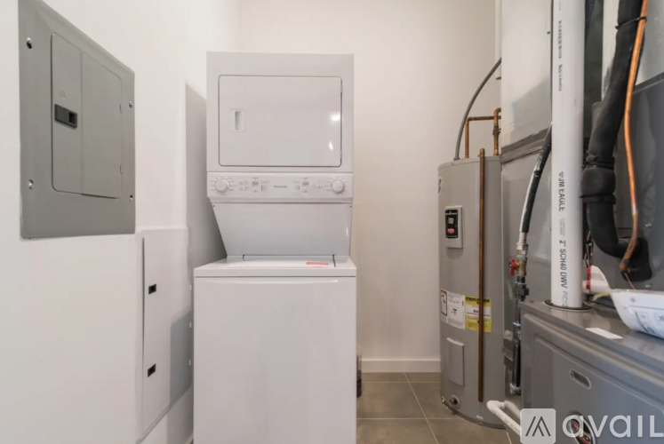 A white dishwasher is in a kitchen next to a microwave and a dryer.