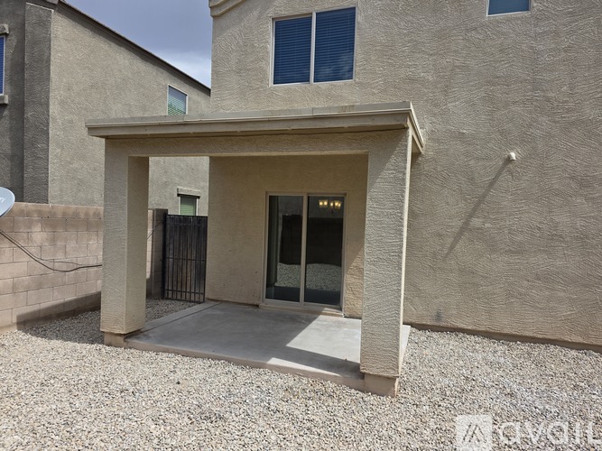 A modern house with a covered entrance and a gravel driveway.