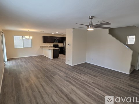A spacious room with a ceiling fan and a kitchen area in the background.