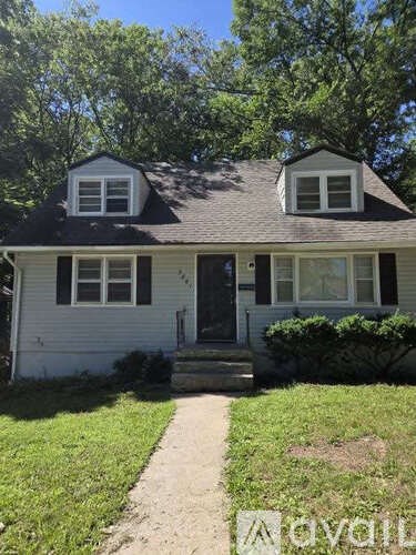 A white house with a black roof and a small front porch.