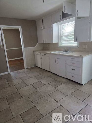 A kitchen with white cabinets and a tiled floor.