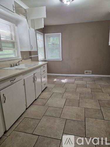 A kitchen with tile flooring and white cabinets.