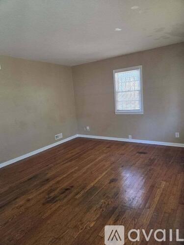 A room with wooden flooring and a window.