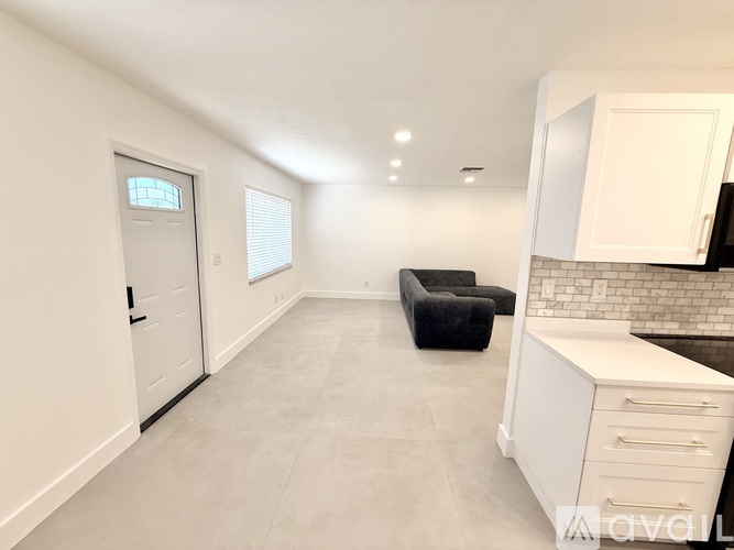 A black chair is in the corner of a white room.