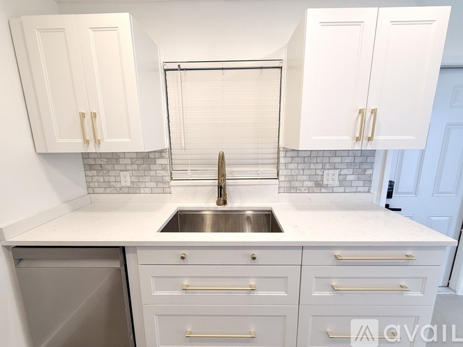 A kitchen with white cabinets and a silver sink.