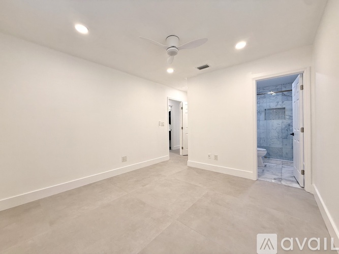 A spacious room with a ceiling fan and a door leading to a bathroom.