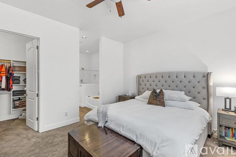 A bedroom with a large bed and a ceiling fan.