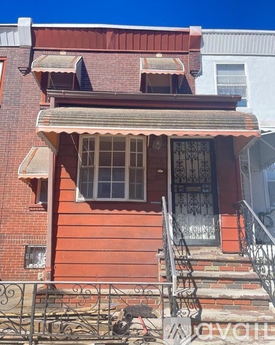 A red brick house with a black iron gate in front.
