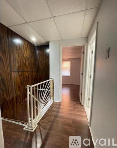 A hallway with wood paneling and a metal railing.