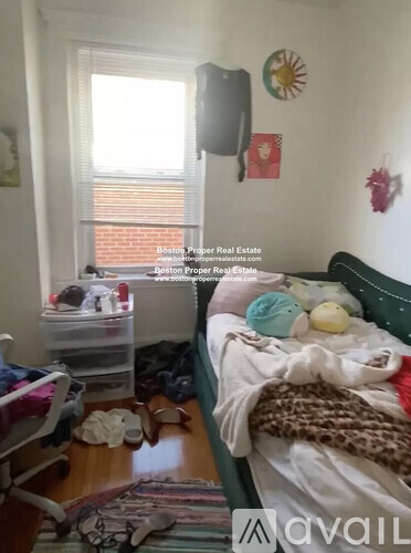 A bedroom with a bed, a chair, and a window with blinds.