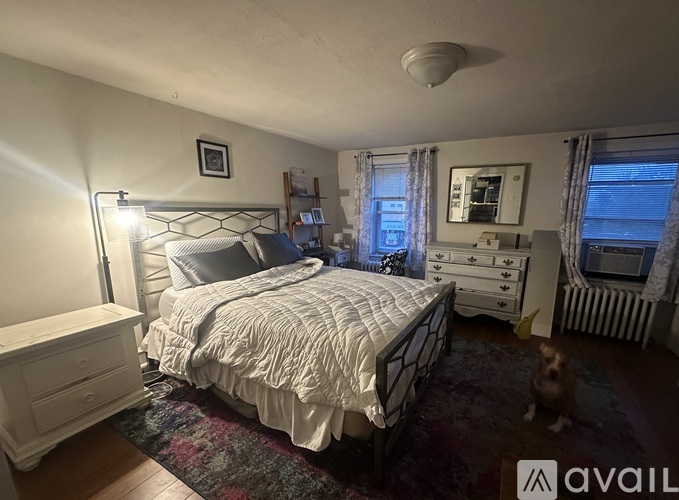 A bedroom with a bed, dresser, and window.