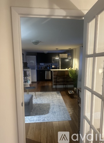 A hallway with a rug and a door leading to a kitchen.